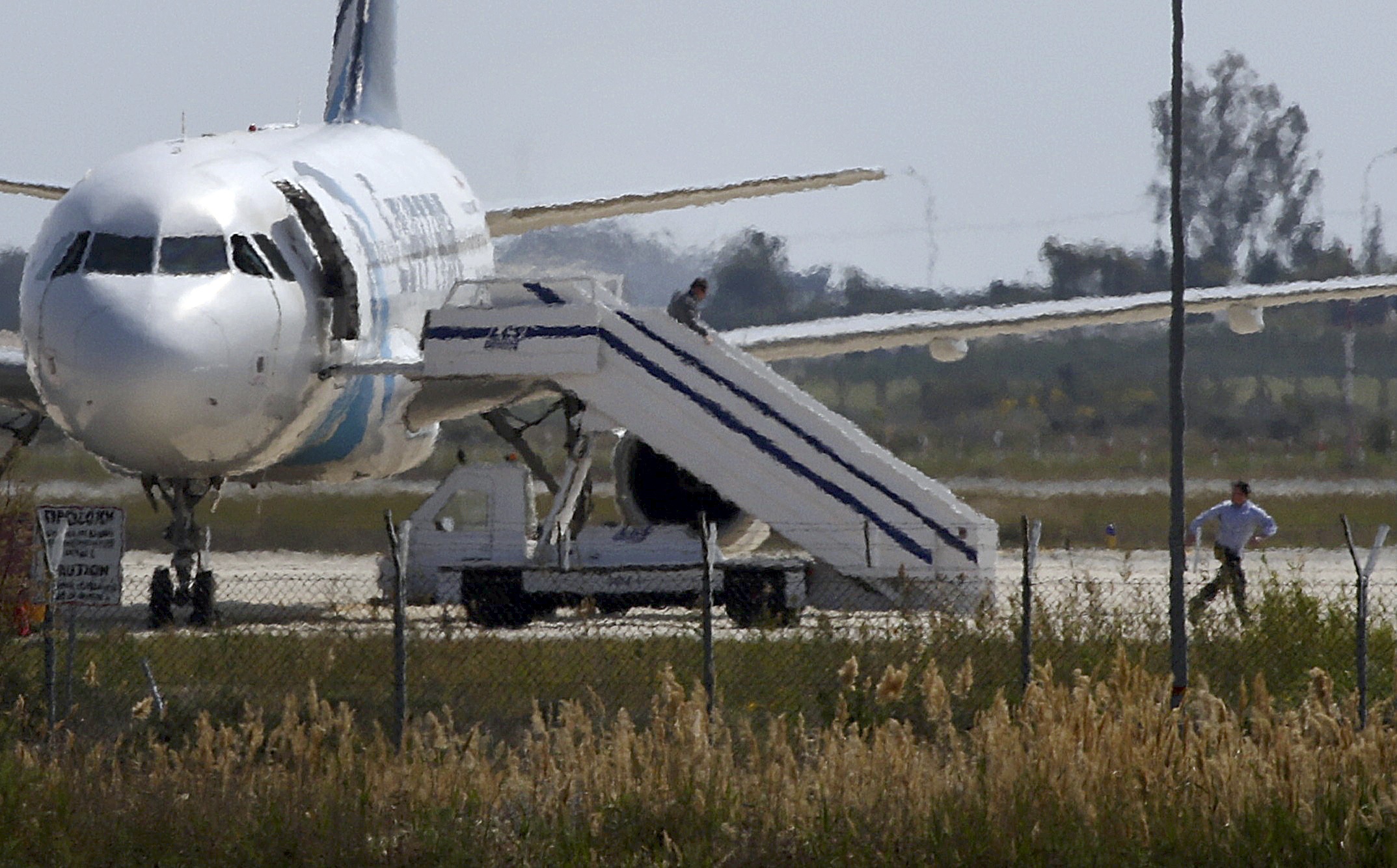 Unidentified people run off the hijacked Egyptair Airbus A320 at Larnaca Airport in Larnaca, Cyprus