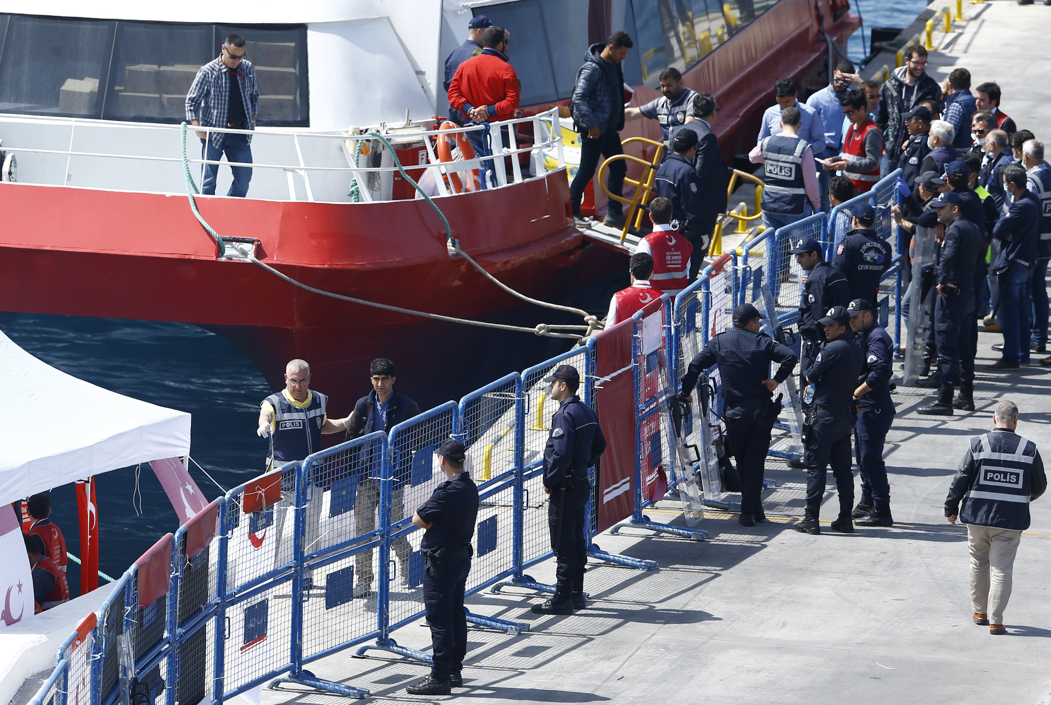 Migrants leave a ferry anchored at port in the Turkish coastal town of Dikili