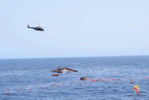 مروحية إيطالية تحوم على موقع الحادثة و عدد من المهاجرين يحاولون النجاة على سطح القارب الغارق - 25 مايو 2016 ( البحرية الايطالية )