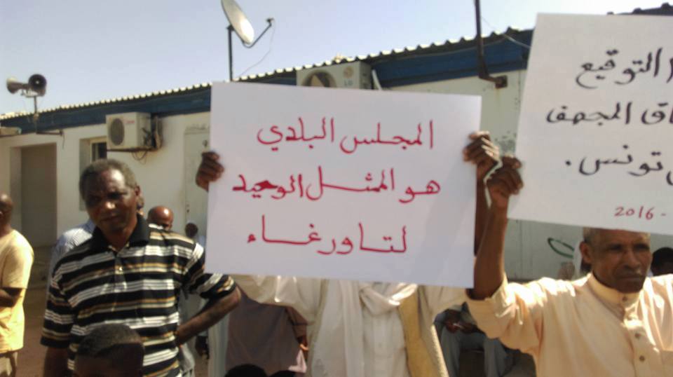 محتج فى مخيم نازحي تاورغاء بمنطقة الفلاح فى طرابلس يرفع لافتة مؤيدة للمجلس البلدي لمدينتهم - طرابلس - 12 أكتوبر 2016